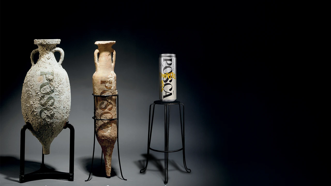 Two ancient-style vases and a can of Posca Hydrate on stands against a dark background