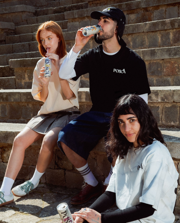 Three people sitting on stone steps, drinking from cans.
